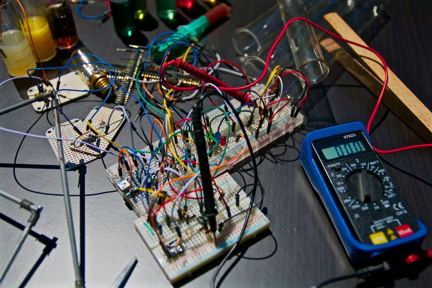 Circuit board on a workbench next to test equipment and hand tools.